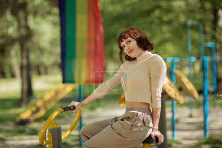 Foto de Feliz y bonita dama en el parque ejercita el gimnasio al aire libre mirando a la cámara y sonriendo muy carismática. - Imagen libre de derechos