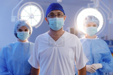 Photo for Portrait of serious diverse surgeons with face masks in operating room in slow motion. Medicine, health and care. v - Royalty Free Image