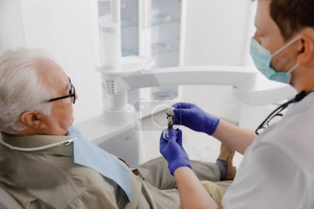 Téléchargez les photos : Vieil homme patient ont un rendez-vous de contrôle à la clinique dentaire le dentiste médecin examinant les dents médecin utilisant des instruments dentaires il vérifie les problèmes de classement. - en image libre de droit