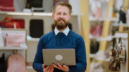 Photo for Small business concept good looking salesman smiling in front of the camera while holding his laptop. - Royalty Free Image