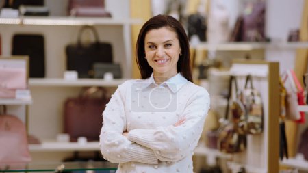 Téléchargez les photos : Concept d'entrepreneur belle dame superviseur posant devant la caméra et croisant les mains et souriant grand dans la boutique d'accessoires. - en image libre de droit