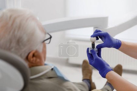 Téléchargez les photos : Professional dentist man treating cavities for a old man at the modern clinic he wearing special glasses for this treatment. - en image libre de droit