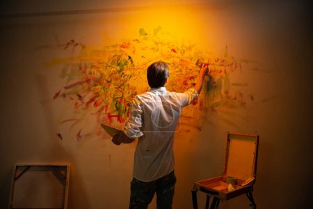 Téléchargez les photos : Artist man painting a contemporary modern artwork on the large wall successfully fine art artist drawing masterpiece. - en image libre de droit