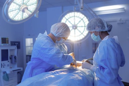 Téléchargez les photos : Prise de vue d'une infirmière qui remet au chirurgien une pièce d'équipement pour l'opération qu'il effectue dans une chambre d'hôpital. - en image libre de droit