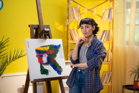 Foto de Una foto baja de una artista de pelo corto pintando algo muy chic y moderno con su pincel sobre un lienzo frente a ella. - Imagen libre de derechos