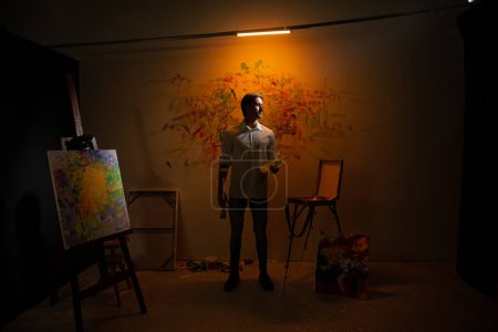 Photo for Concept of contemporary and modern artwork the artist man closeup to the camera mixed his oil colour on the palette with the brush. - Royalty Free Image