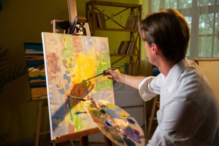 Foto de Carismático joven artista de la pintura en el lienzo nuevo cuadro que utiliza el color al óleo de su concepto de paleta de la educación artística. - Imagen libre de derechos
