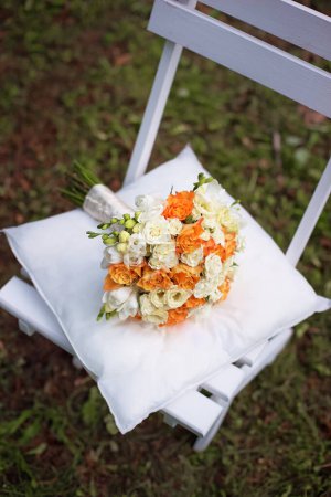 Téléchargez les photos : Bouquet de roses de mariée sur une chaise blanche dans le parc
. - en image libre de droit