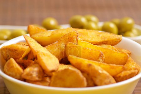 Photo for Fried potato wedges with olives on background - Royalty Free Image