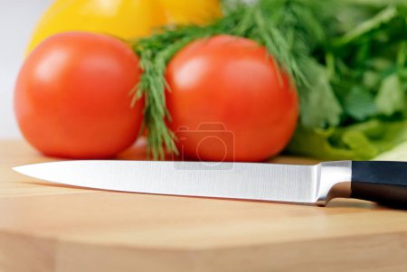 Foto de Tabla de cortar con tomate, perejil y cuchillo - Imagen libre de derechos
