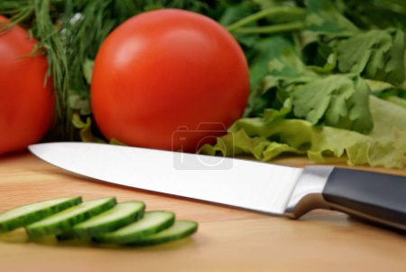 Photo for Chopping board with tomato, cucumber, parsley and knife - Royalty Free Image
