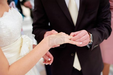 Téléchargez les photos : Amour et mariage. Une cérémonie de mariage. Gros plan du marié mettant une bague dorée sur le doigt de la mariée
. - en image libre de droit