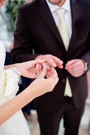 Téléchargez les photos : Amour et mariage. Une cérémonie de mariage. Gros plan de la mariée mettant une bague d'or sur le doigt du marié. - en image libre de droit