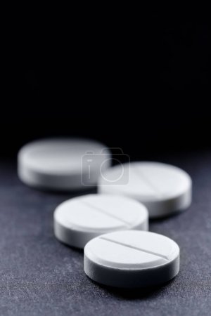Foto de Concepto de medicina y drogas. Macro tiro de píldoras blancas manojo sobre fondo negro con copyspace. - Imagen libre de derechos