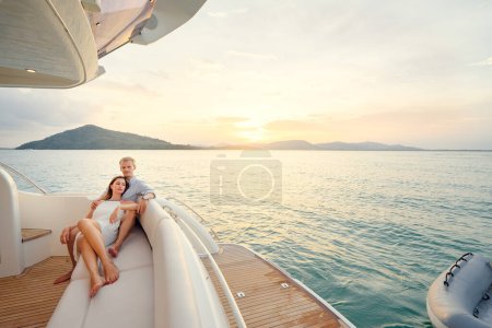 Téléchargez les photos : Vacances romantiques et voyages de luxe. Jeune couple amoureux assis sur le canapé sur le pont yacht moderne. Naviguer sur la mer
. - en image libre de droit