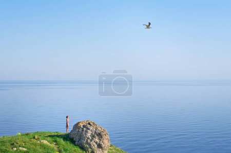 Photo for Young woman looking at the sea with a gull in the sky. - Royalty Free Image