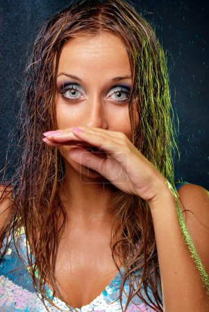 Foto de Sorprendida cara de mujer húmeda con gotas de agua en luces de colores - Imagen libre de derechos