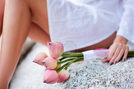 Téléchargez les photos : Femme tenant bouquet de lotus sur la plage tropicale. - en image libre de droit