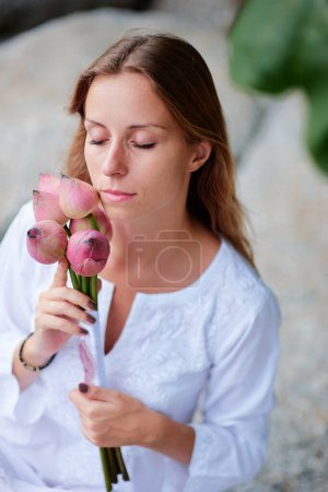 Téléchargez les photos : Portrait de belle jeune femme tenant bouquet de lotus sur la plage tropicale. - en image libre de droit