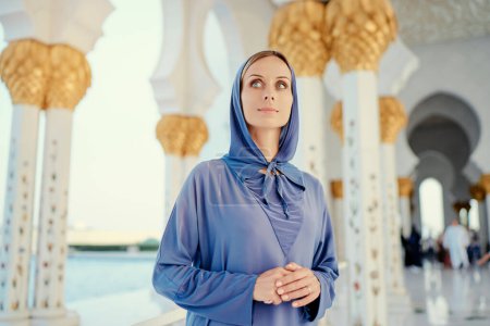 Foto de Viajar por Emiratos Árabes Unidos. Mujer en Abaya tradicional de pie en la mezquita Sheikh Zayed Grand, famoso Abu Dhabi turismo. - Imagen libre de derechos