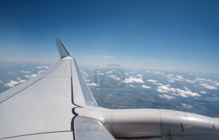Photo for Wing of modern aircraft flying in cloudy blue sky during trip - Royalty Free Image