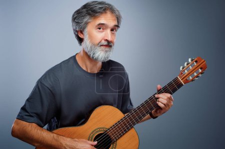 Photo for Aged bearded man with an acoustic guitar - Royalty Free Image
