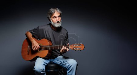 Photo for Aged bearded man with an acoustic guitar - Royalty Free Image