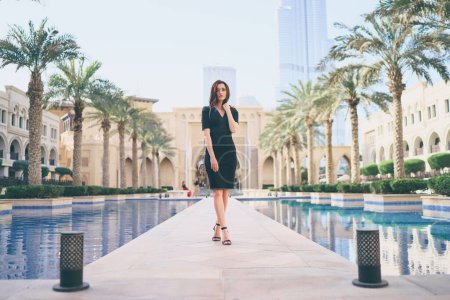 Photo for Beautiful young woman with charming smile and long hair walking on Dubai Downtown. - Royalty Free Image