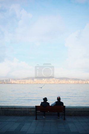 Téléchargez les photos : Beautifil paysage avec des hommes assis sur le banc sur le bord de la mer, Istanbul Turquie - en image libre de droit