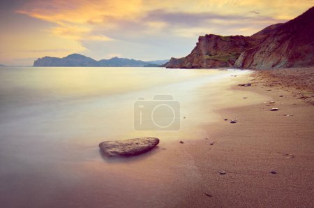 Beautiful sunset landscape with calm sea and mountains in the background.