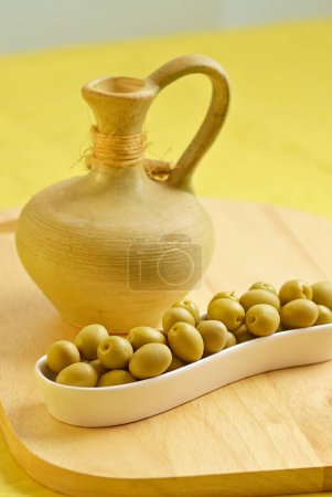 Olives en jeu blanc avec un pot sur la plaque de bois
