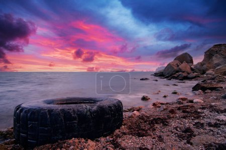 Photo for Old car tires on the shore. Water and sea coast pollution car tires on sand beach. - Royalty Free Image
