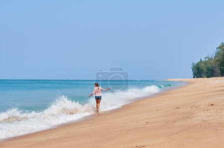 Téléchargez les photos : Vacances sur le rivage. Jeune femme marchant sur la plage tropicale bénéficiant d'une belle vue. - en image libre de droit