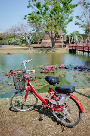 Foto de Bicicleta Roja estacionada cerca del lago en el parque histórico de Sukhothai - Imagen libre de derechos