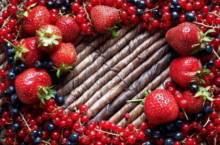 Erdbeeren, Johannisbeeren und Blaubeeren rahmen die rustikale Oberfläche ein.