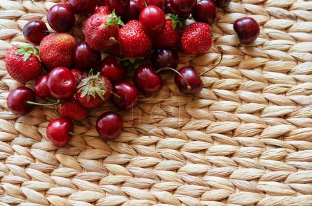 Strawberries, and cherries on the rustic surface.