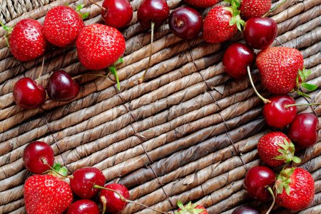 Strawberries, cherries on the rustic surface.