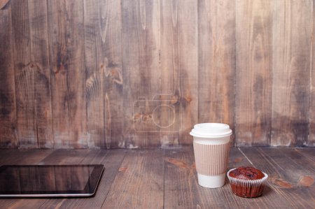 Téléchargez les photos : Je travaille au café. Tablette, tasse de café et muffin en papier sur la table en bois. - en image libre de droit