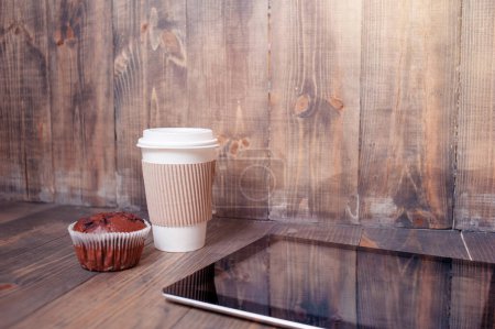 Photo for Working at cafe. Tablet computer, paper cup of coffee and muffin on the wooden table. - Royalty Free Image