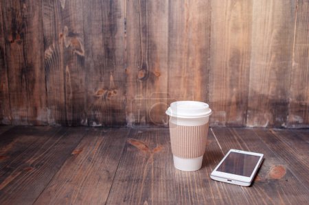 Téléchargez les photos : Tous les jours essentiels. Coupe en papier de café et smartphone sur le fond en bois. - en image libre de droit