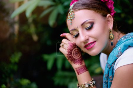 Foto de Hermosa mujer india joven en ropa tradicional con maquillaje nupcial y joyas. hermosa novia tradicionalmente vestida al aire libre en la India. Bailarina de bollywood en Sari y henna en las manos - Imagen libre de derechos