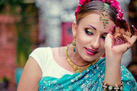 Photo for Beautiful young caucasian woman in traditional indian clothing sari with bridal makeup and jewelry and henna tattoo on hands. - Royalty Free Image