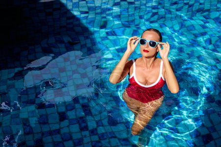 Photo for Summer vacation and fashion. Beautiful young woman in red swimsuit at swimming pool. - Royalty Free Image