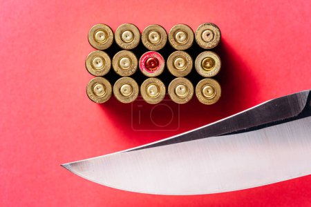 Photo for Knife and cartridges on a red background. - Royalty Free Image