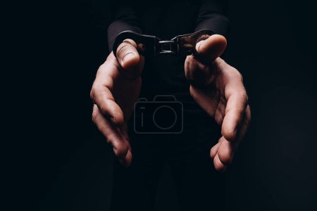A man in handcuffs on a black background.