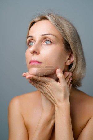 Skin care. Blonde woman with beauty face facial massage. No makeup. Grey background.