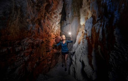 Jeune femme explorant une grotte creusée dans la montagne.