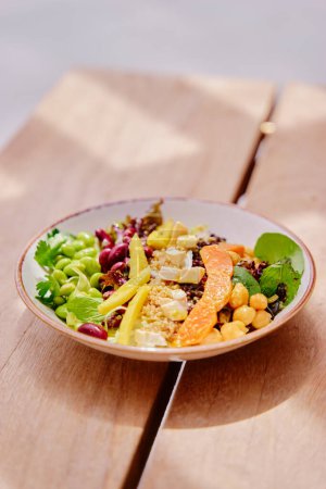 Photo for Salad with pumpkin, mango, beans,  lettuce and tofu on a wooden table. Healthy vegetarian food. - Royalty Free Image