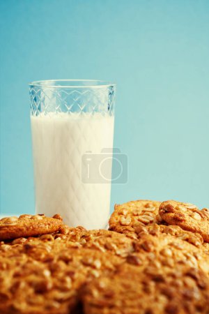 Foto de Galletas fritas con vaso de leche sobre fondo azul claro. - Imagen libre de derechos