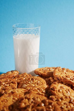 Téléchargez les photos : Biscuits aux copeaux avec verre de lait sur fond bleu clair. - en image libre de droit